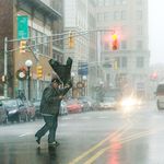 A man's umbrella flips from the strong wind as he crosses Sip Avenue on Journal Square in Jersey City.